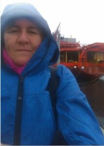Me dressed in blue raincoat with hood on and the ship in the background.