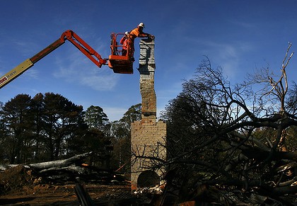 Man on cherry picker dismantling a chimney